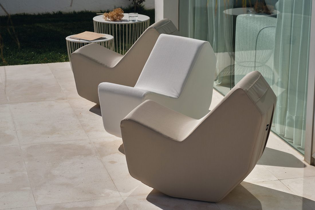 Fauteuils lounge beige et blanc installés sur une terrasse contemporaine avec table d’appoint et baie vitrée.