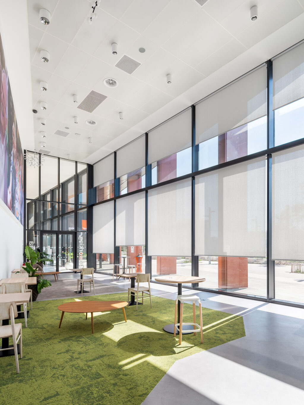 Stores enrouleurs intérieurs en membrane composite souple Serge Ferrari sur façade vitrée de bâtiment tertiaire