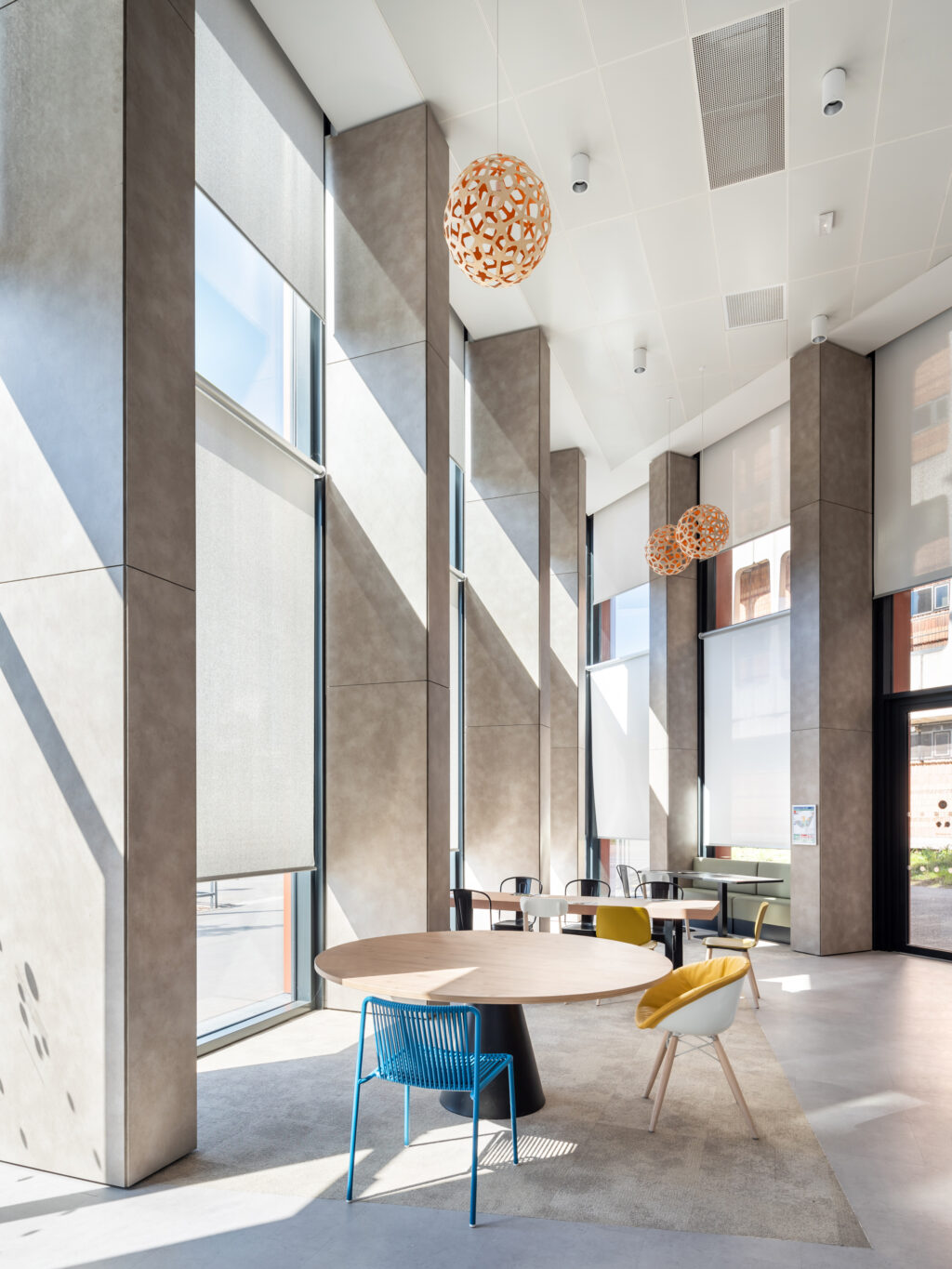 Stores enrouleurs grand format en membrane composite souple Serge Ferrari pour contrôle solaire et lumière naturelle