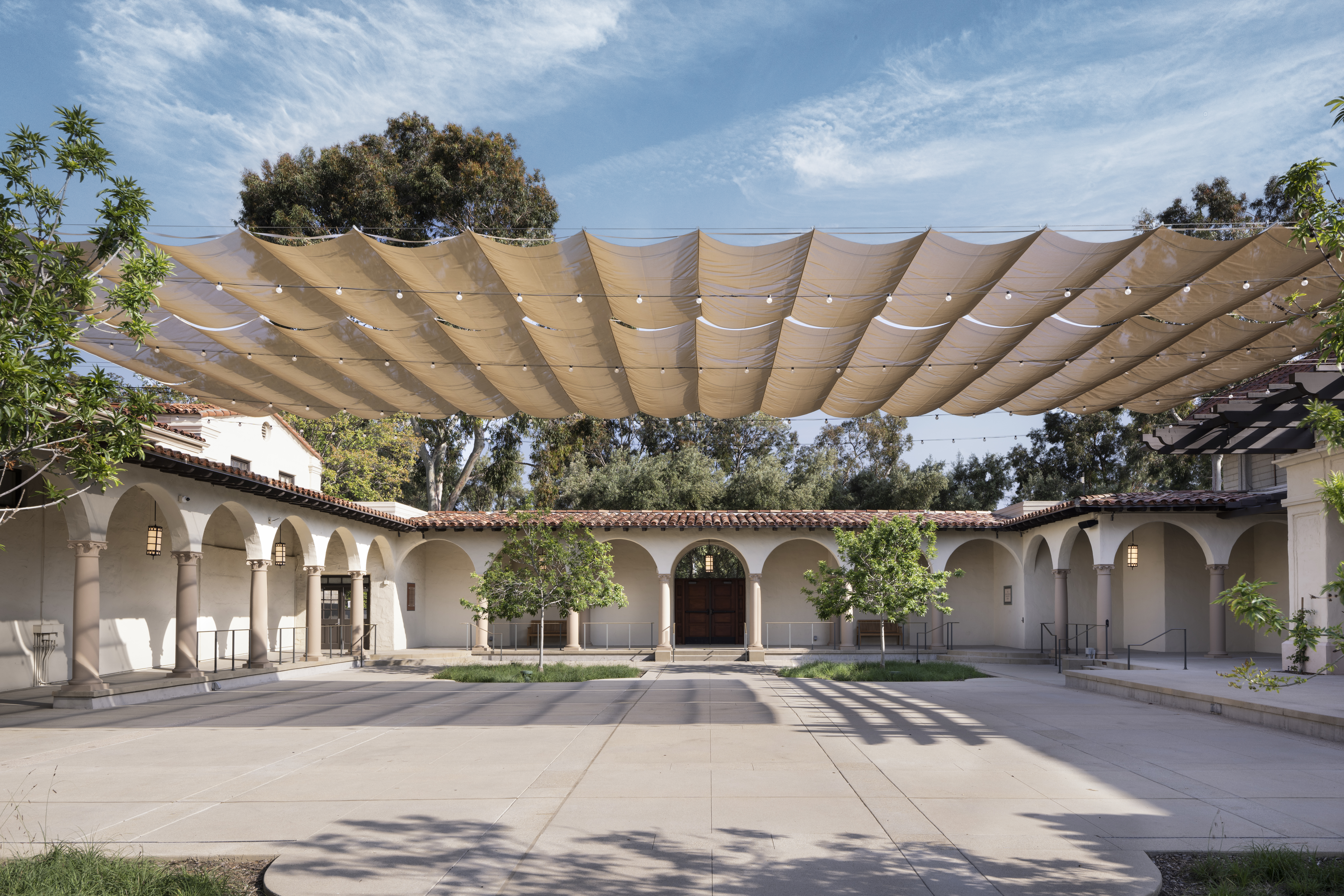 Wide view of Cannon Plaza courtyard with shade canopy extended above the open paving and surrounding arches.