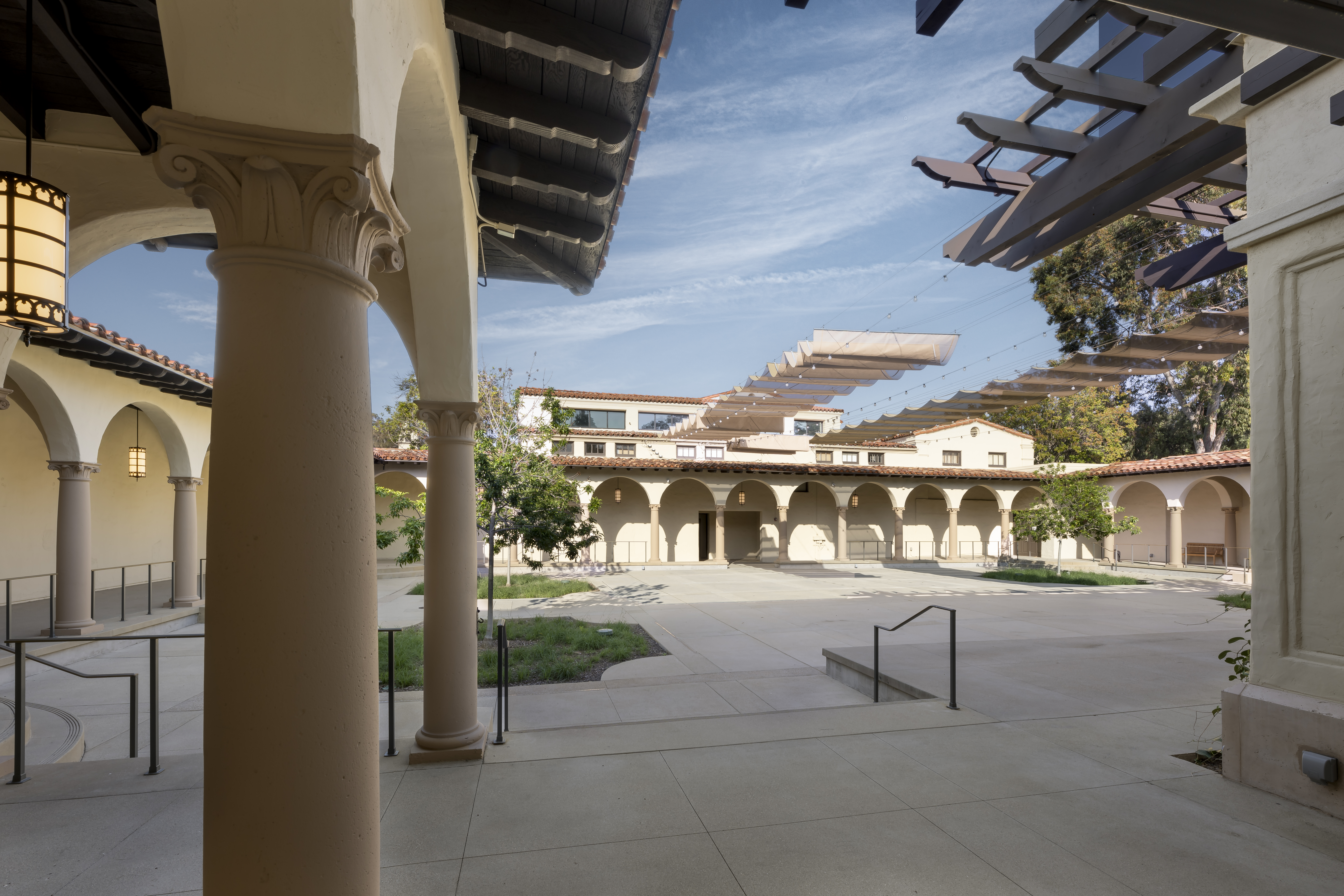 Corner view into Cannon Plaza courtyard from under an arch, with canopy panels and arcades across the open space.