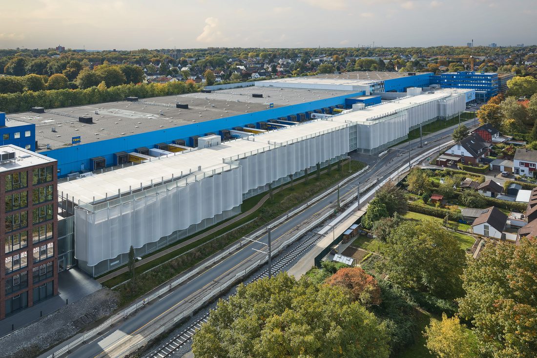 Façade textile 3D en membrane tendue enveloppant un bâtiment industriel de grande longueur