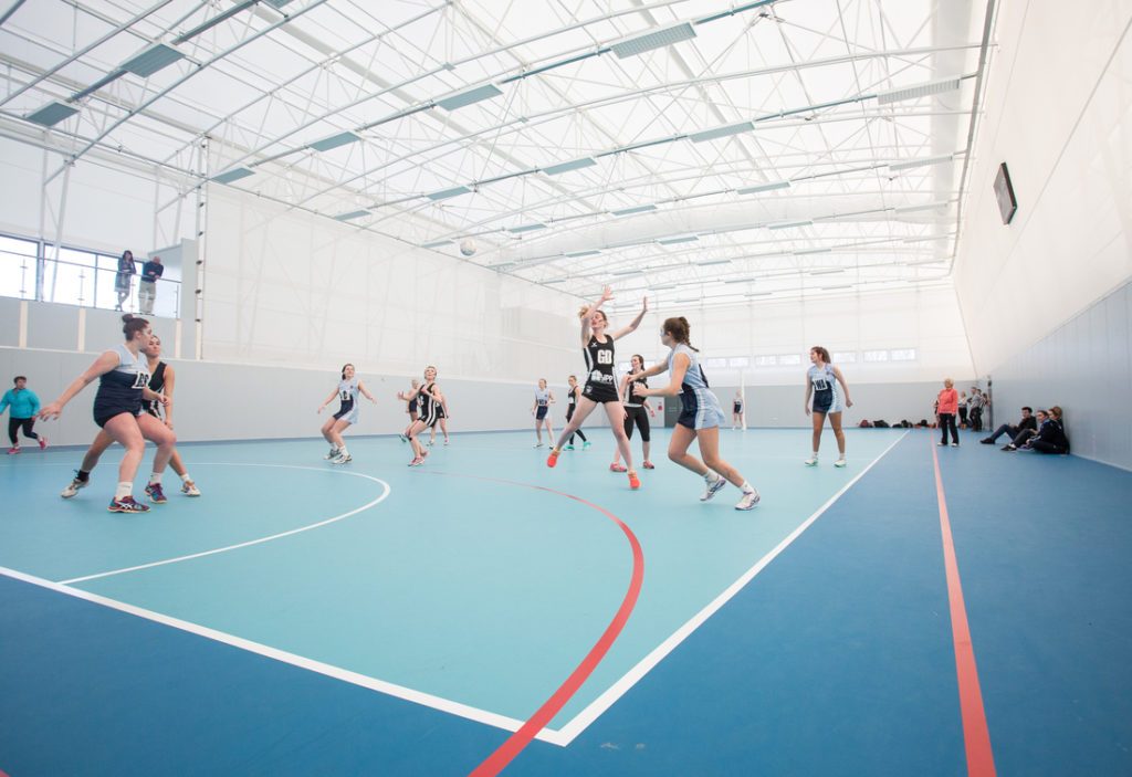 Salle de sport indoor avec toiture en membrane textile Serge Ferrari assurant lumière naturelle et confort acoustique.