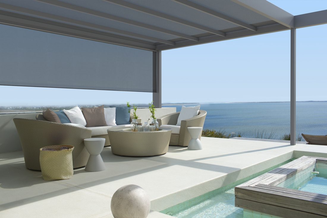 Pergola haut de gamme au bord de l’eau avec piscine, revêtue d’une toile composite Serge Ferrari.