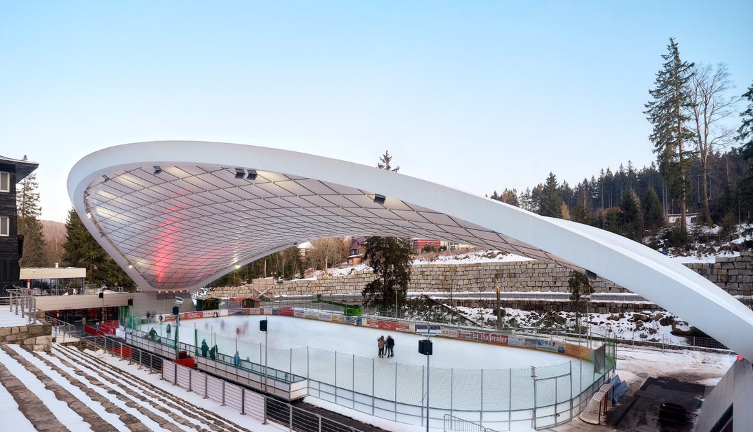 Curved tensile canopy covering the Schierker Feuerstein Arena ice rink in winter conditions