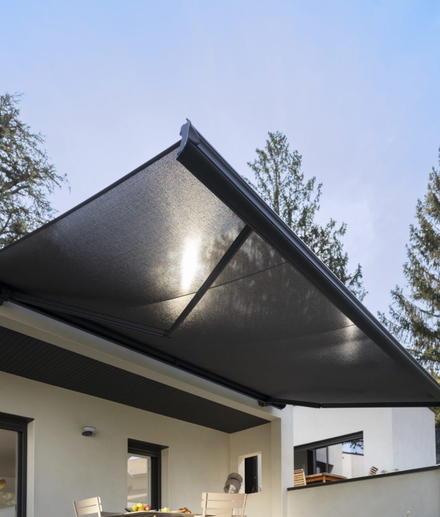 Store banne noir en membrane composite souple Soltis Serge Ferrari filtrant le soleil au-dessus d’une terrasse