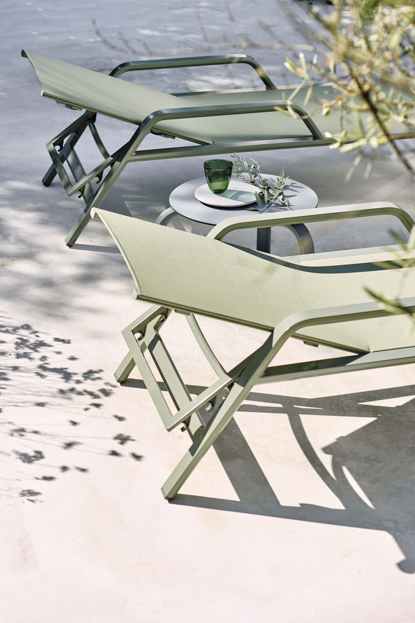 Transats verts en sling au bord d'une piscine