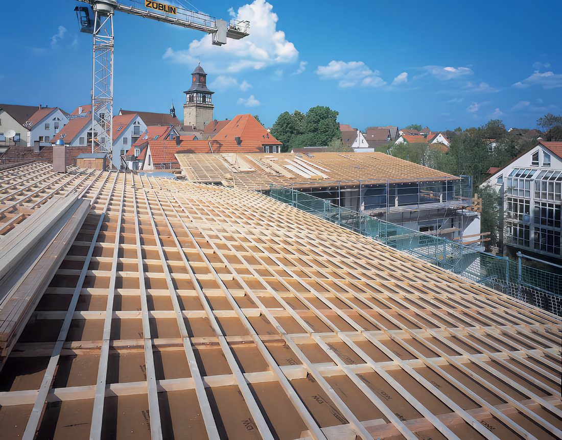 Toiture en bois en cours de construction avec pose du lattage et membrane Stamisol, sur un chantier en zone urbaine.