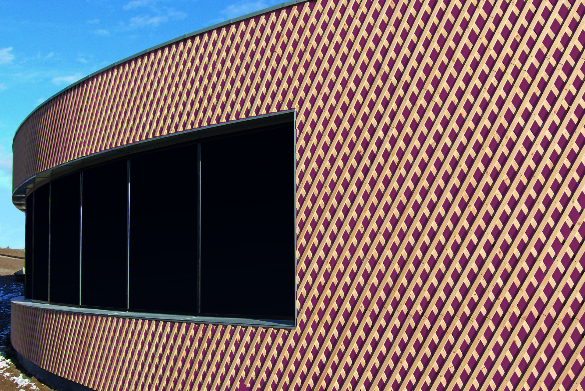 Façade courbe recouverte d’un bardage ajouré en motif losange, avec une grande baie vitrée sombre ; membrane Stamisol en sous-face derrière le bardage.