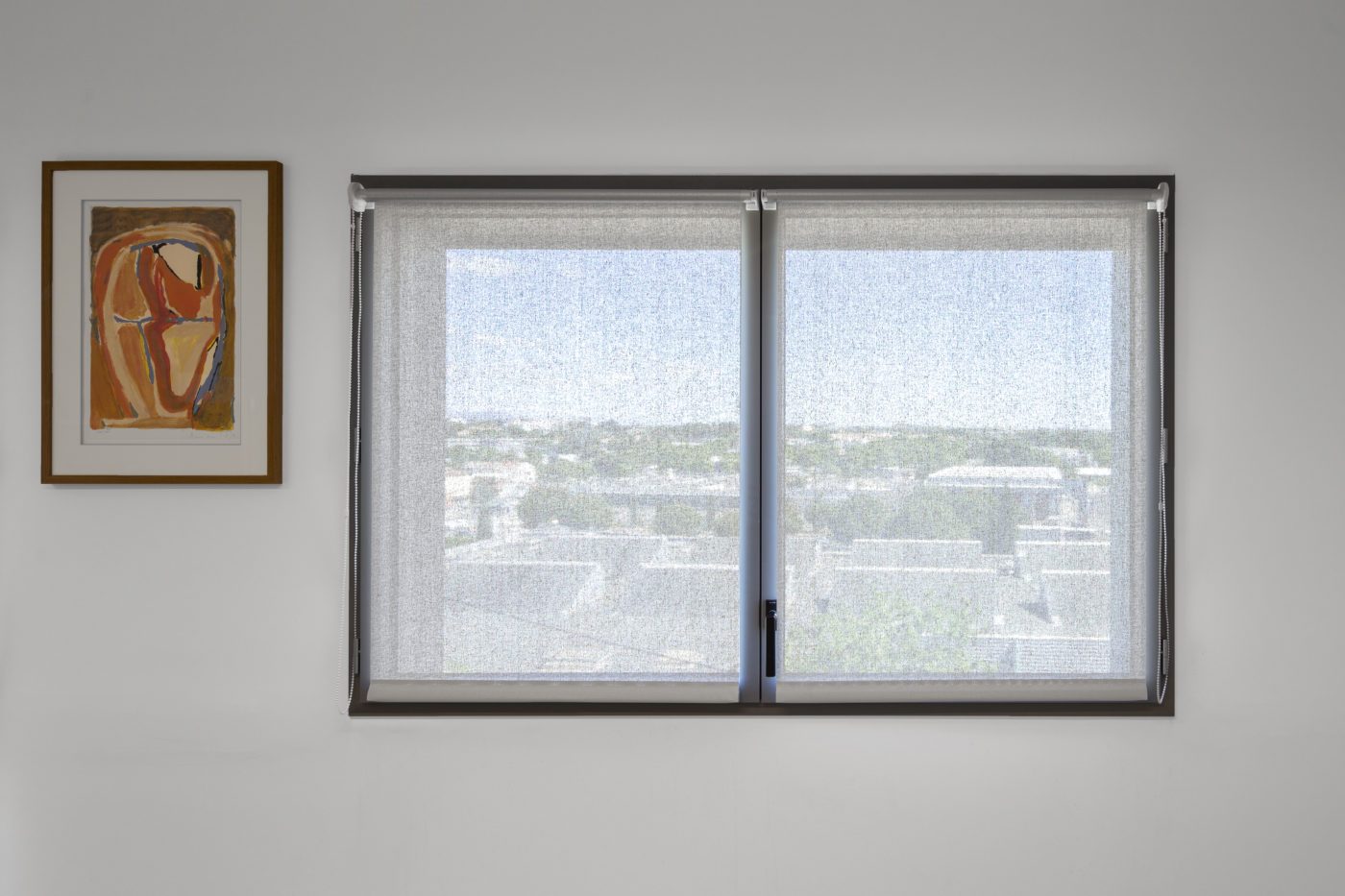 Store enrouleur intérieur en toile technique Serge Ferrari sur fenêtre à deux vantaux, filtrant la lumière pour réduire l’éblouissement.