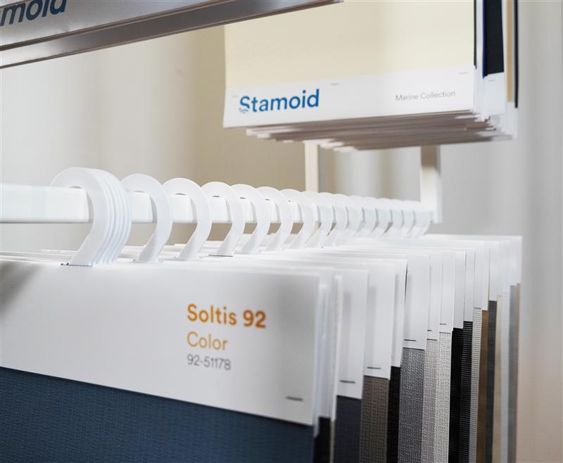 Cintres d’échantillons de toiles présentés sur un totem PLV du Groupe Serge Ferrari.