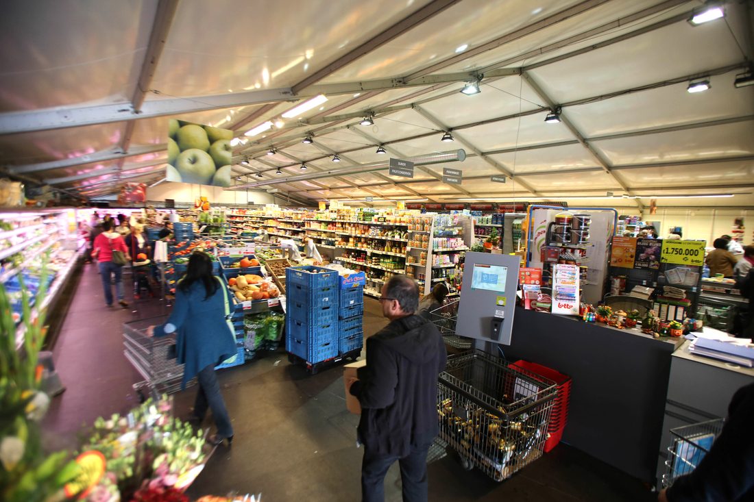 Magasin temporaire installé sous une structure en membrane composite souple Serge Ferrari, offrant une couverture textile durable et lumineuse.