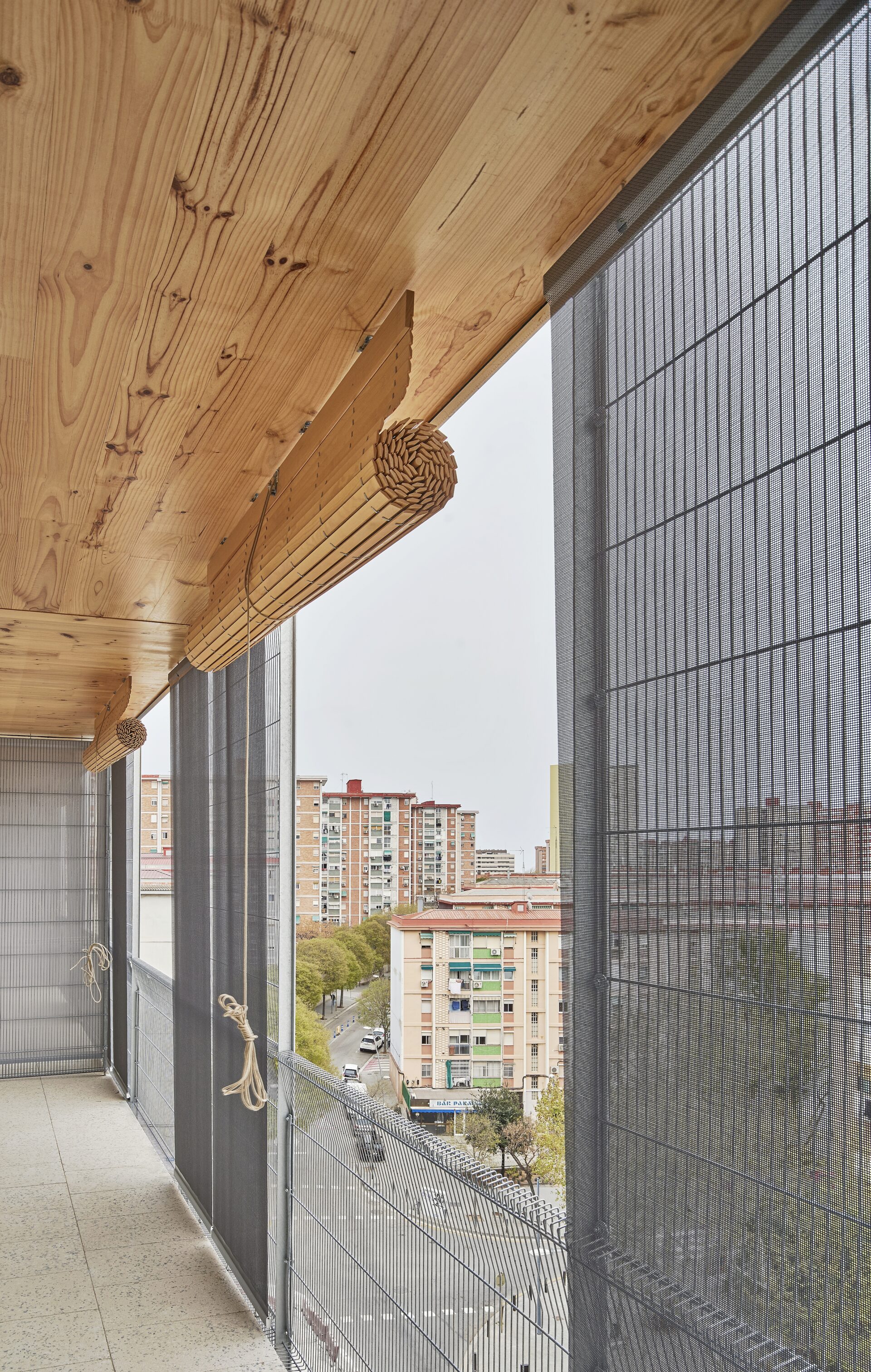 Balcon avec brise-soleil en bois et façade textile technique Serge Ferrari à Cornellà