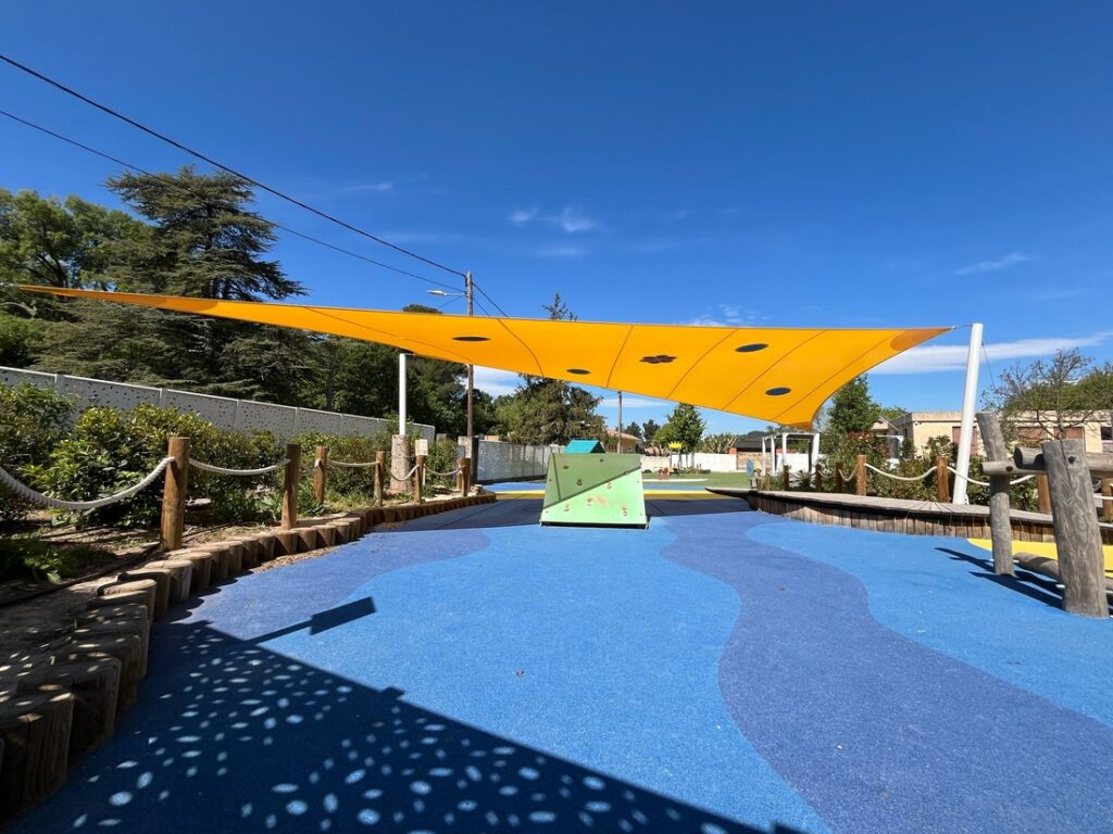 Toile d'ombrage Soltis 86 de couleur jaune. Projet de protection solaire pour les jeunes enfants dans une école maternelle.