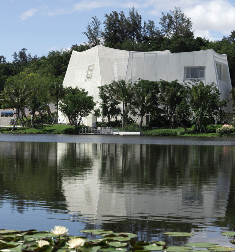 Bâtiment contemporain en bord de lac avec façade textile translucide et membrane tendue.