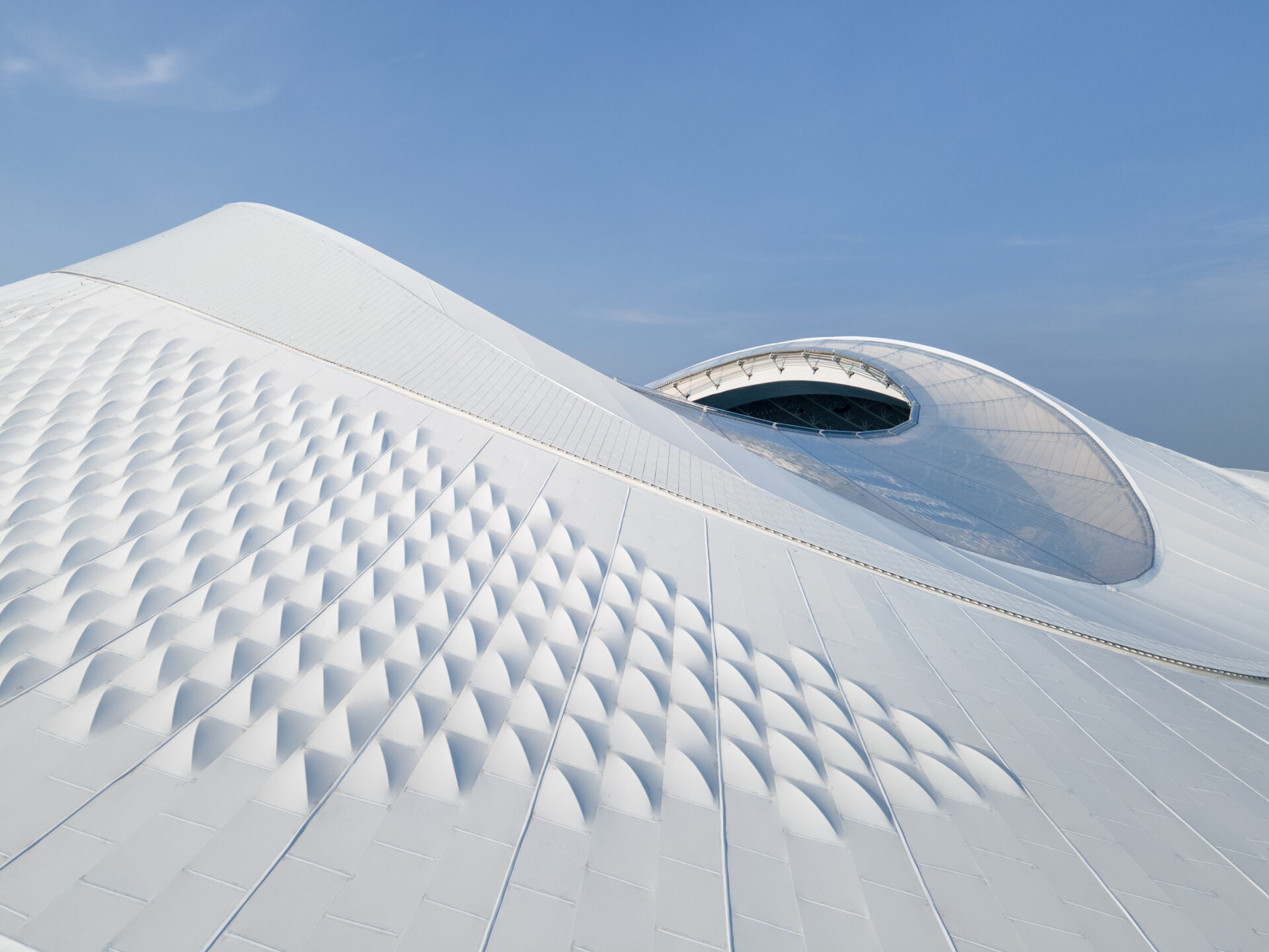 Façade extérieure du stade de Xiamen Bailu avec enveloppe blanche aux motifs géométriques.