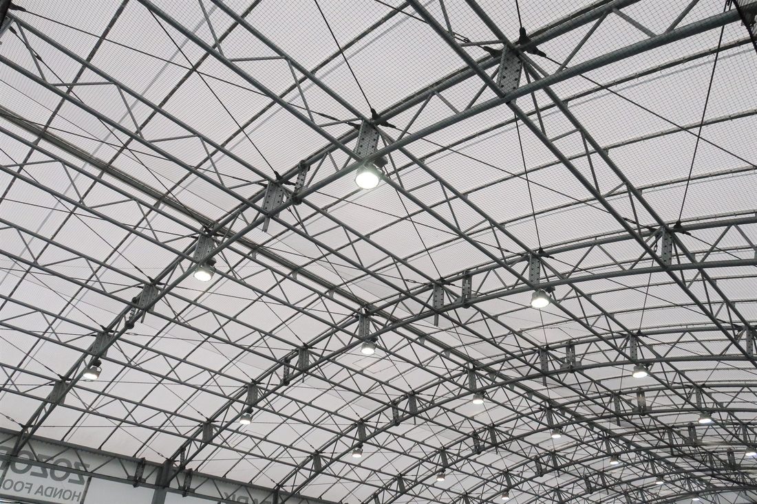 Toiture en membrane composite souple Serge Ferrari sur structure métallique, offrant une couverture légère et lumineuse pour un espace sportif.