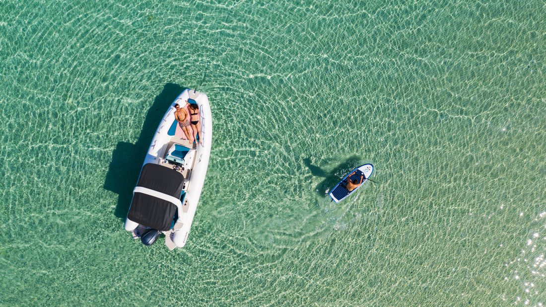 Bateau semi-rigide et paddle sur eau turquoise vus du ciel