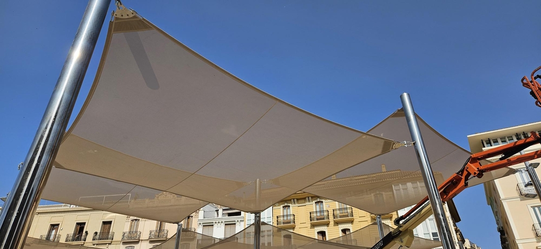 Voiles d'ombrage en Tenseo Frontside 381, tendues sur une structure en acier inoxydable dans un espace public.